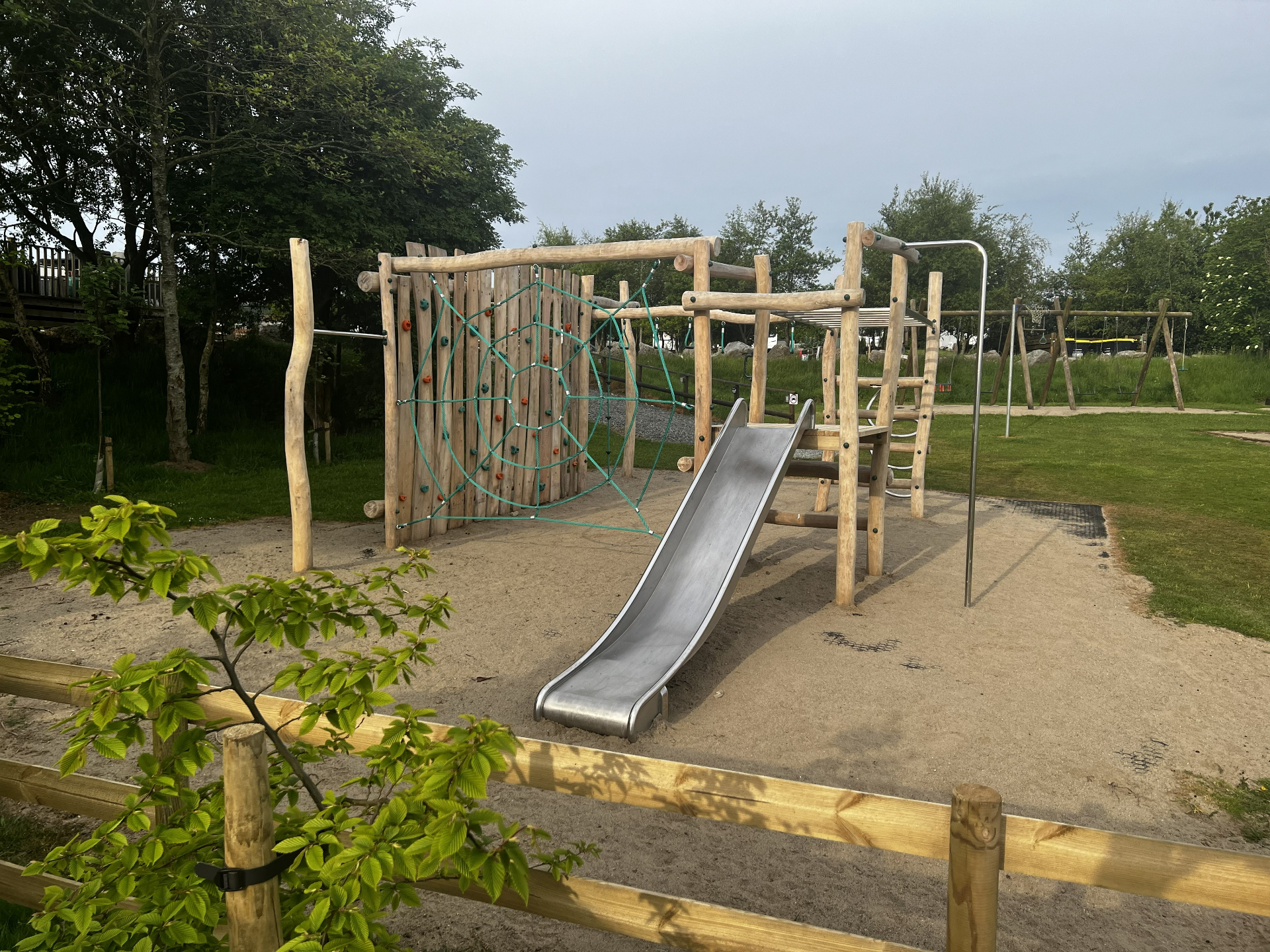 Wooden climbing frame with rope web and slide at Pen Parc